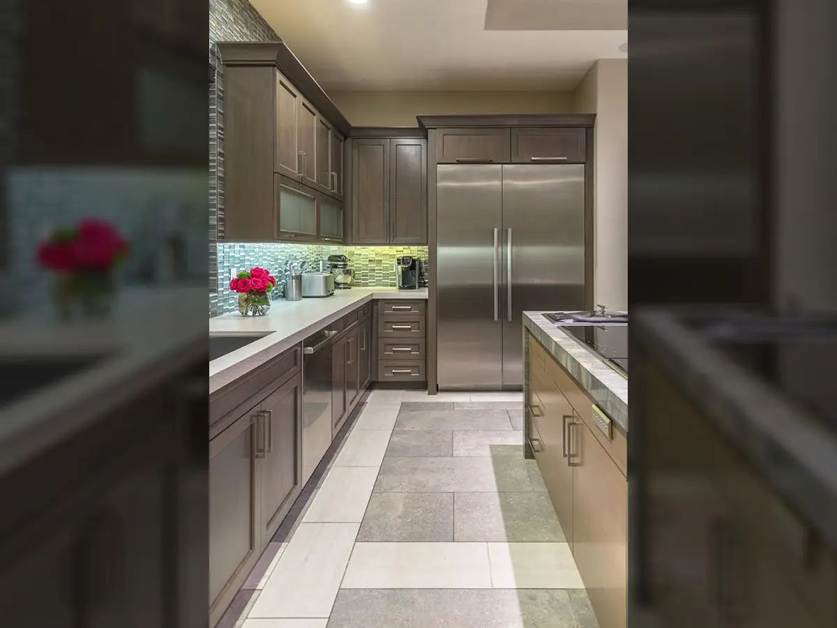 A kitchen with stainless steel appliances and tile flooring.
